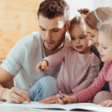 family sitting at a table coloring on a piece of paper